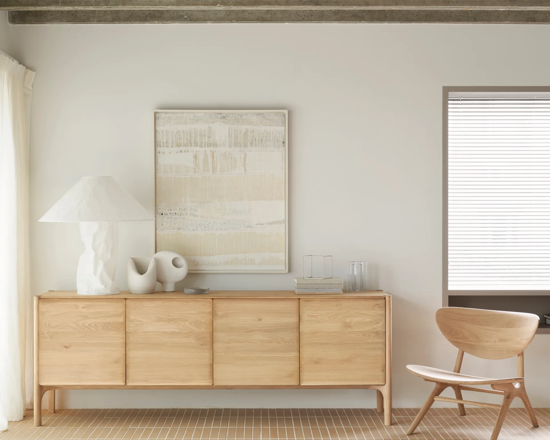 Ethnicraft light oak sideboard with four doors and a matching low chair with a curved seat, in a minimalist room.