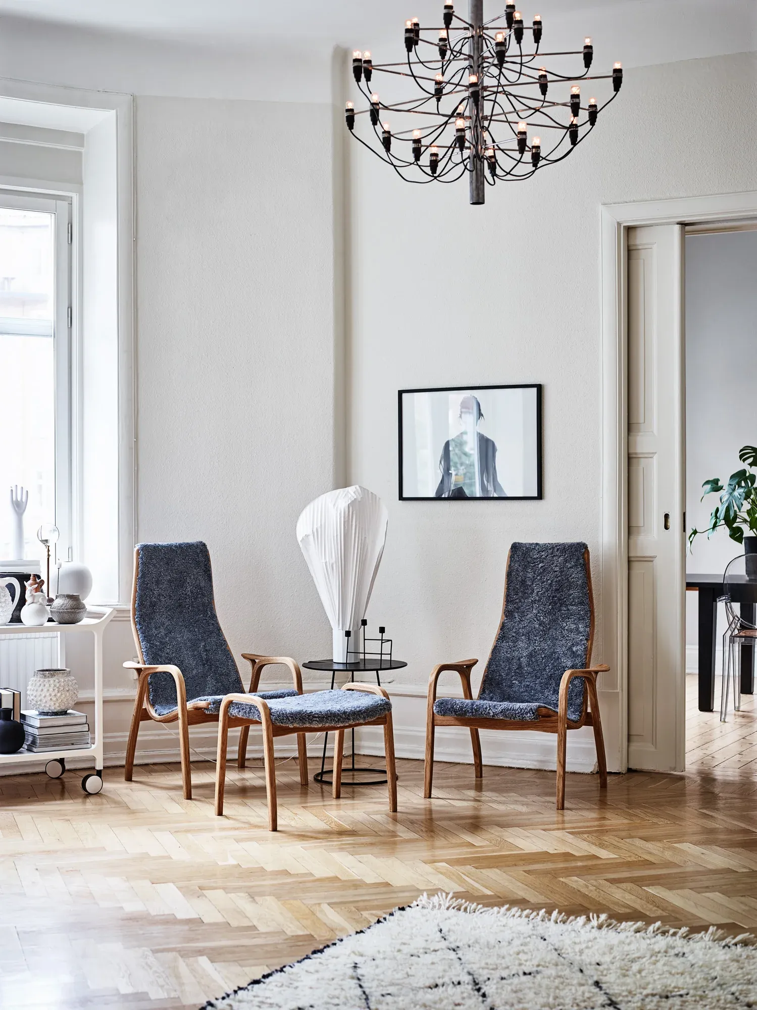 Two Swedese armchairs and a footstool with wooden frames and dark blue upholstery in a bright living room with wood floor.