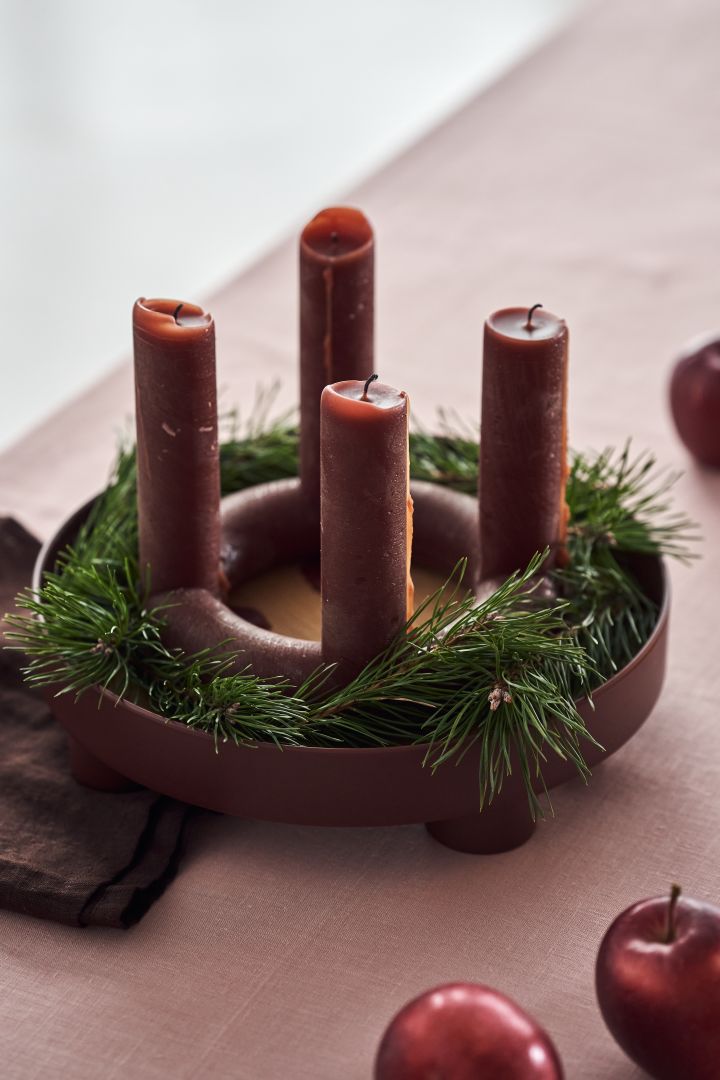How to decorate with traditional Scandinavian Christmas decorations - The red Lucia Advent candle from Broste Copenhagen sits in the Platform tray from Muuto surrounded by sprigs of evergreen creating a lovely centrepiece for the Christmas table. 