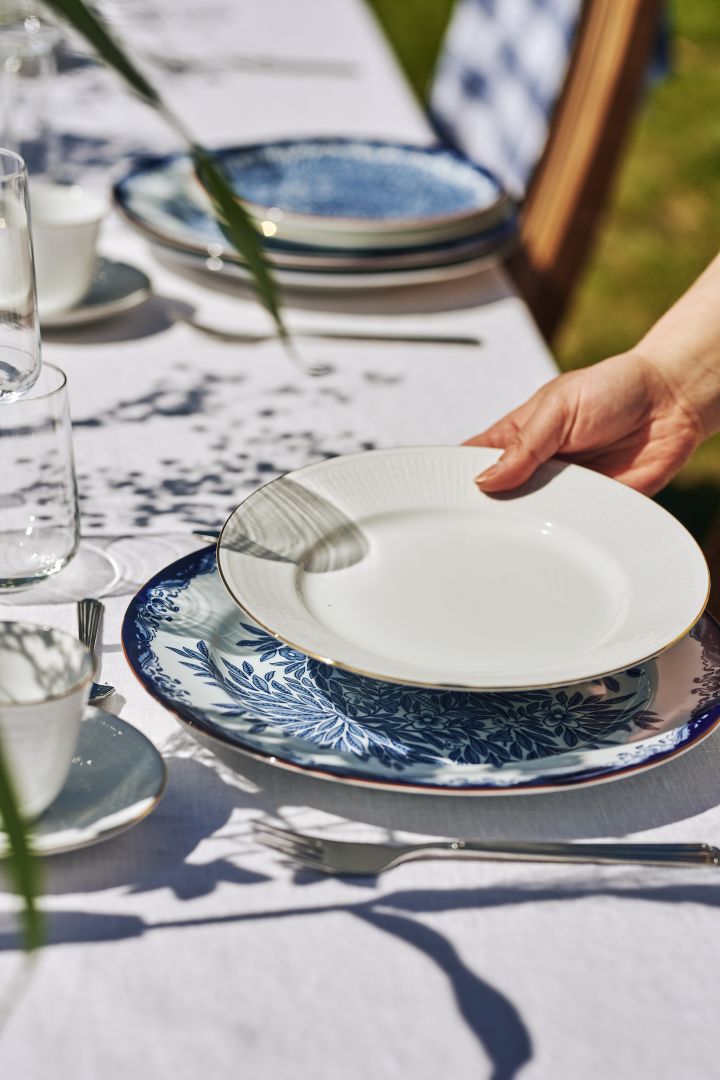 A traditional Midsummer table setting in blue and white with the Swedish Grace Gala plate with a gold outline.