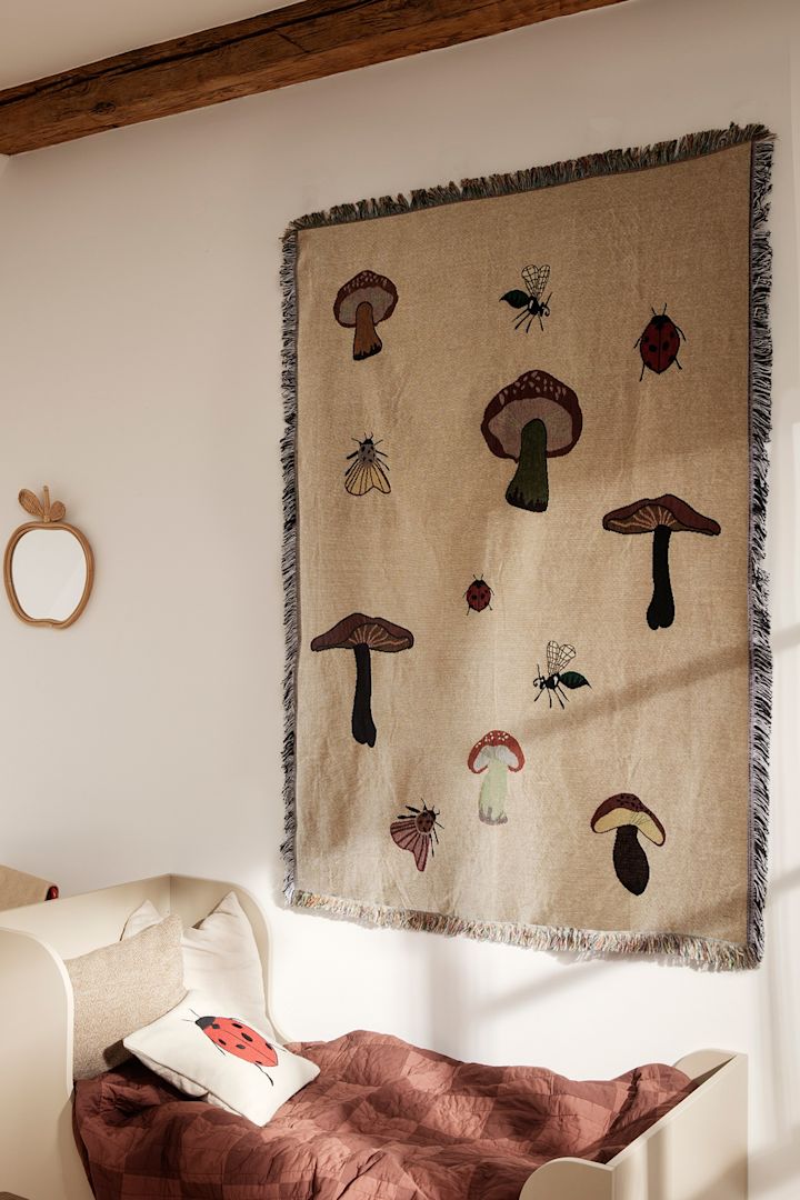 A children's room decorated with motif's of mushrooms with a wall hanging from Ferm Living - highlighting nature as one of the Scandinavian  interior design trends for 2023. 