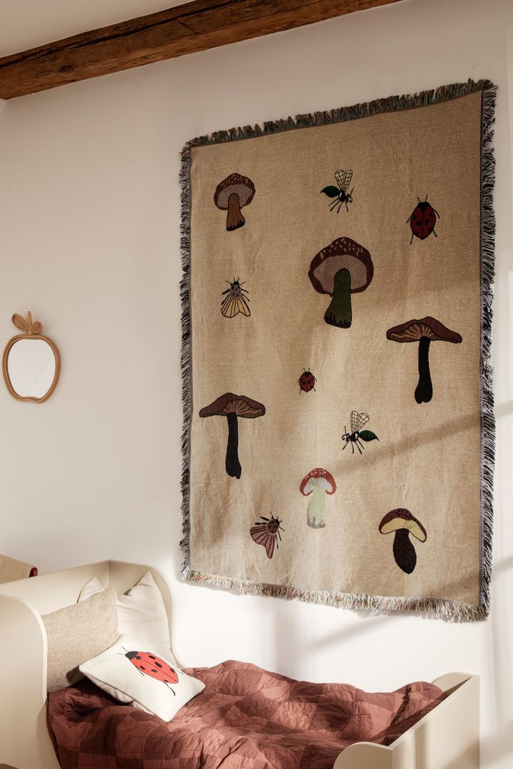 A children's room decorated with motif's of mushrooms with a wall hanging from Ferm Living - highlighting nature as one of the Scandinavian  interior design trends for 2023. 