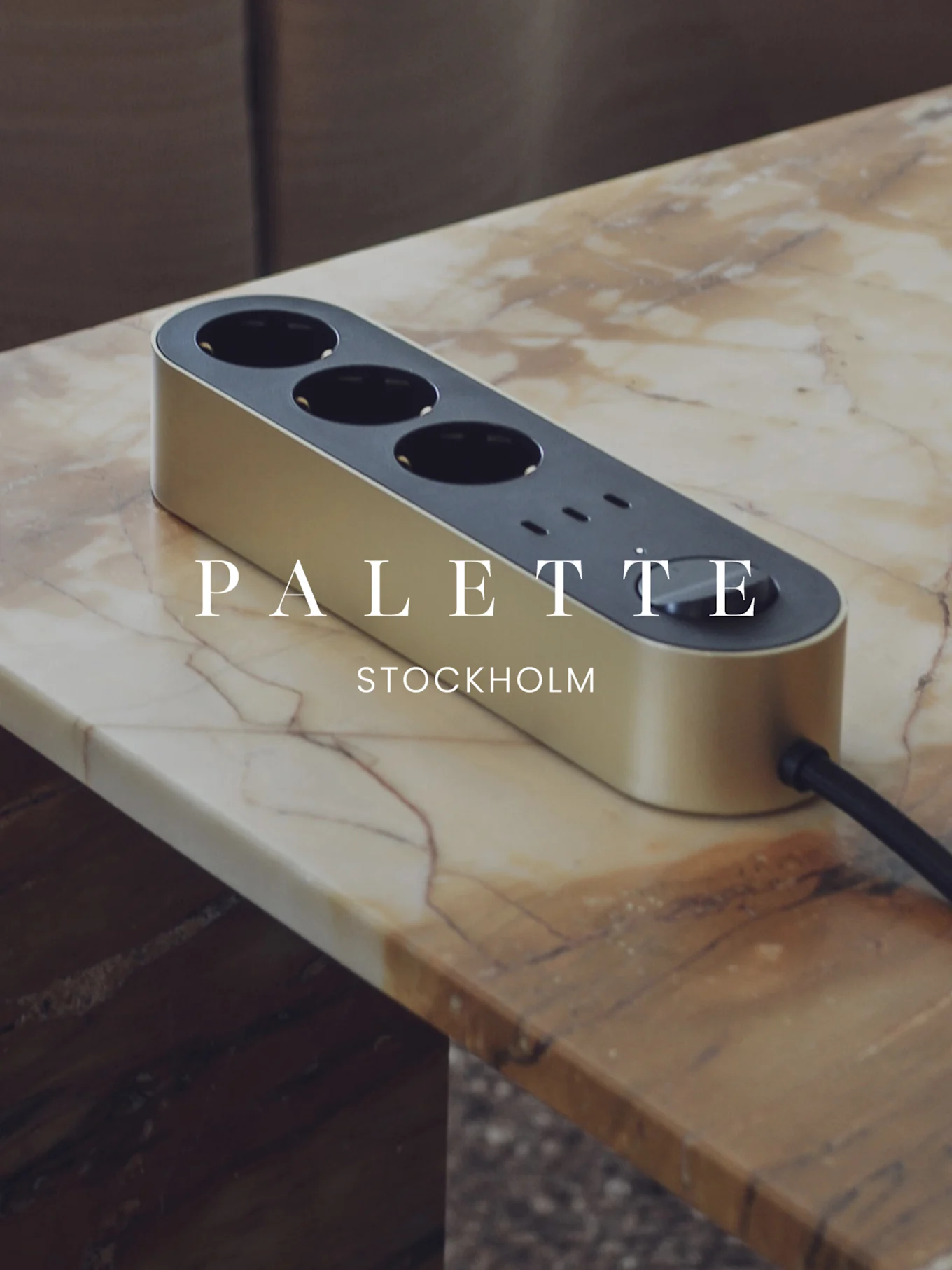Golden power strip with three outlets and three USB ports on a marble table.