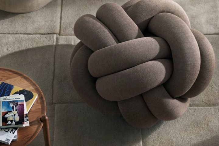 The Knot Cushion XL in brown photographed from above with a coffee table. 