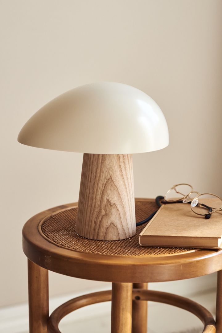 The Night Owl table lamp from Fritz Hansen sits on a wooden stool with a book and reading glasses. 