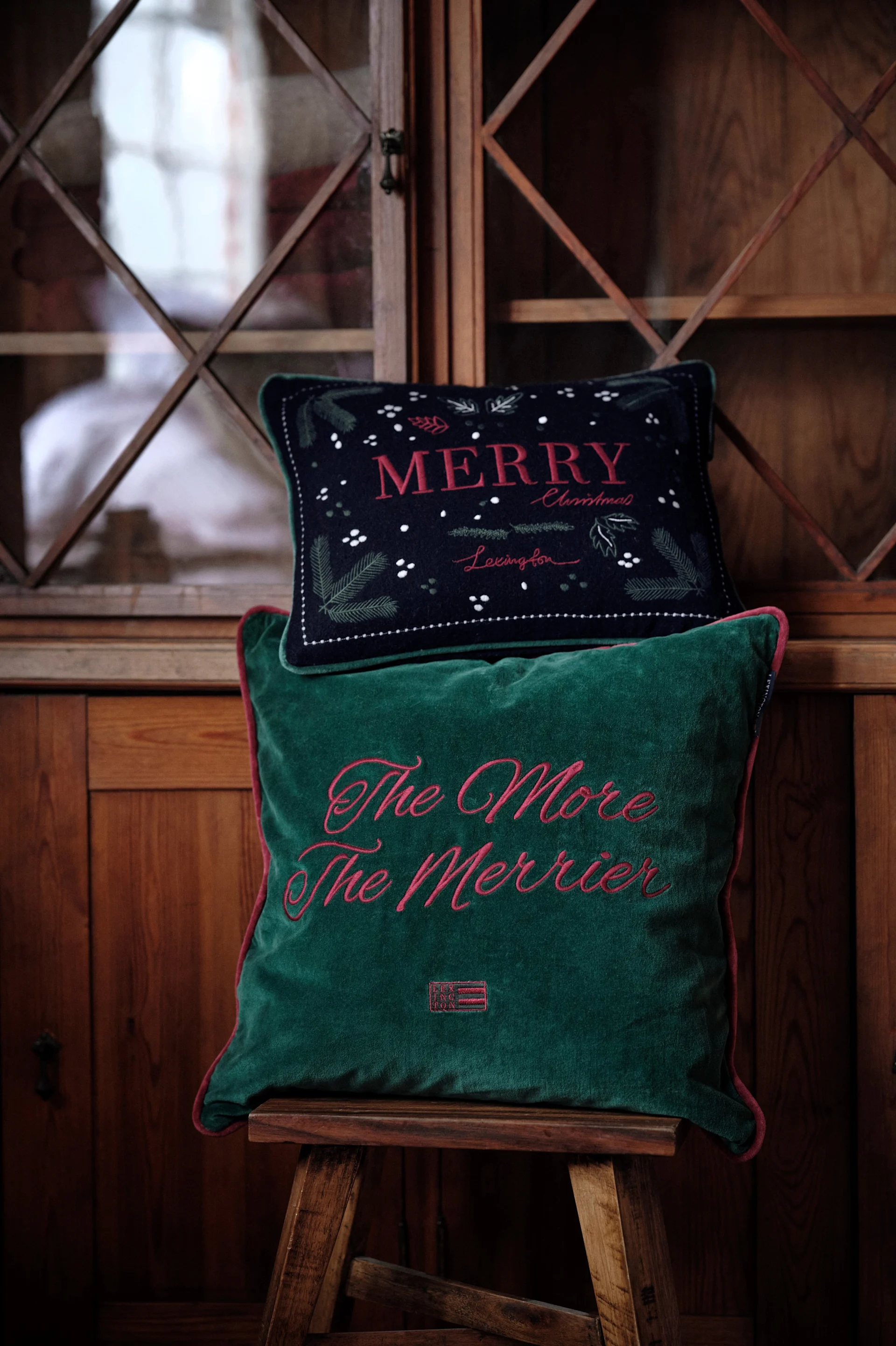 Cushions are a popular Christmas decoration in 2025: here are two festive cushions from Lexington on a stool.