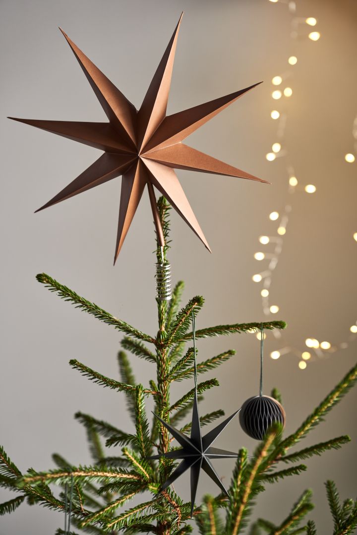 Decorate the Christmas tree with Christmas tree decorations for 2021 in 4 different styles according to Nest Trends - Nurture, Share, Boost and Cultivate. Here you see the tree topper from Broste Copenhagen in a golden brown colour next to a set of string lights.
