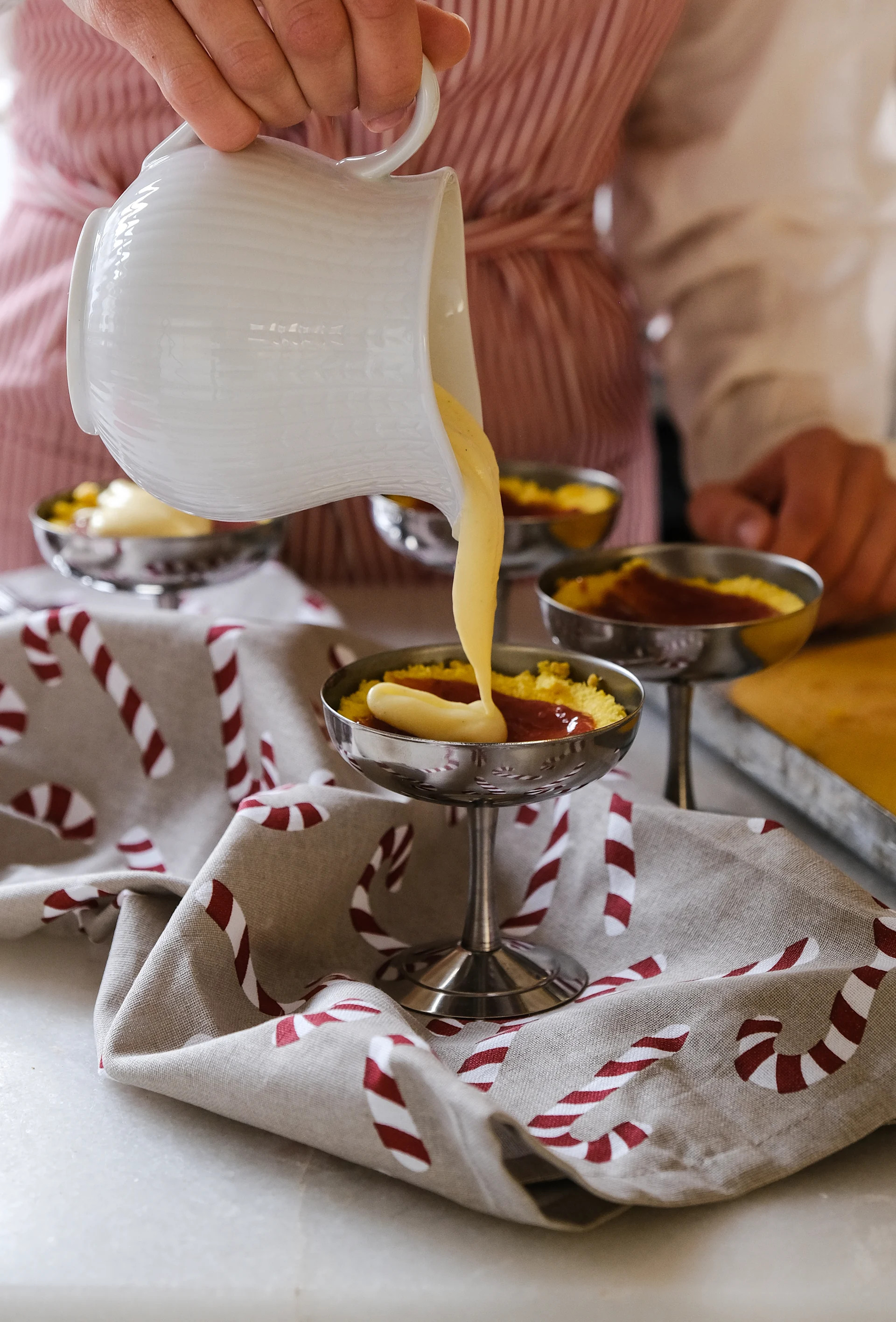 Frida pours vanilla cream into serving bowls on stands to demonstrate a recipe for Swedish princess cake with saffron, part of a recipe for Swedish Christmas baking.