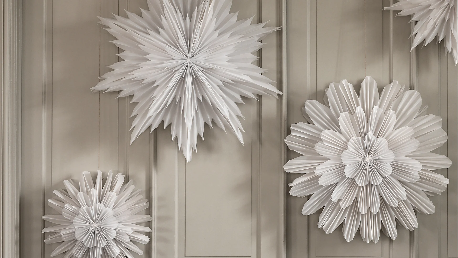 Paper star lanterns hanging in a group against a beige wardrobe. 