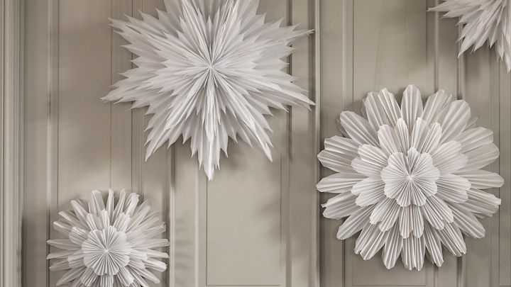 Paper star lanterns hanging in a group against a beige wardrobe. 