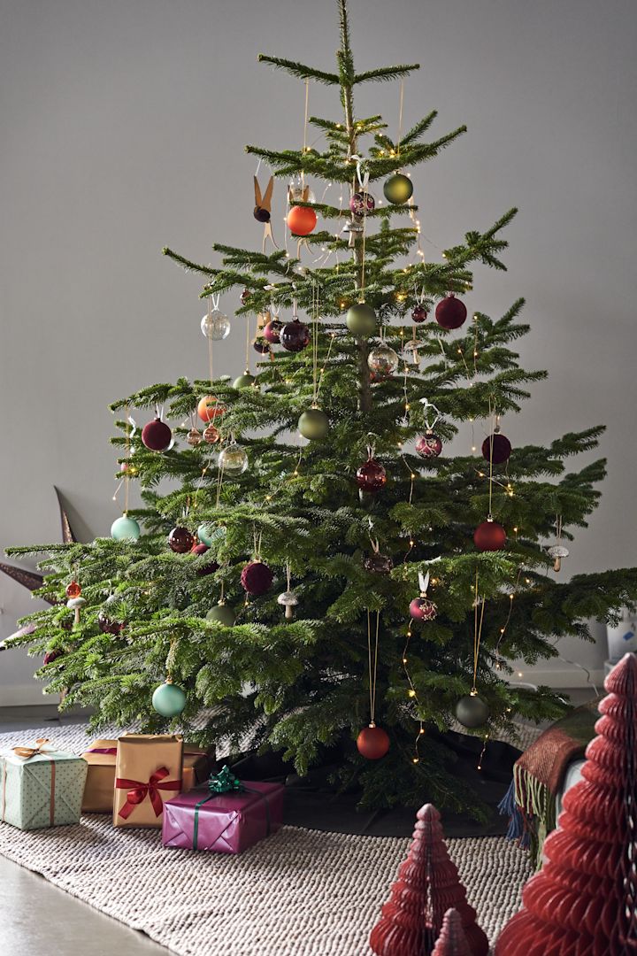 Decorate the Christmas tree with Christmas tree decorations for 2021 in 4 different styles according to Nest Trends - Nurture, Share, Boost and Cultivate. Here you see a magnificent tree on Scandi Living Flock wool rug in beige with decorations in deep rich colours and shades of red, orange and green.