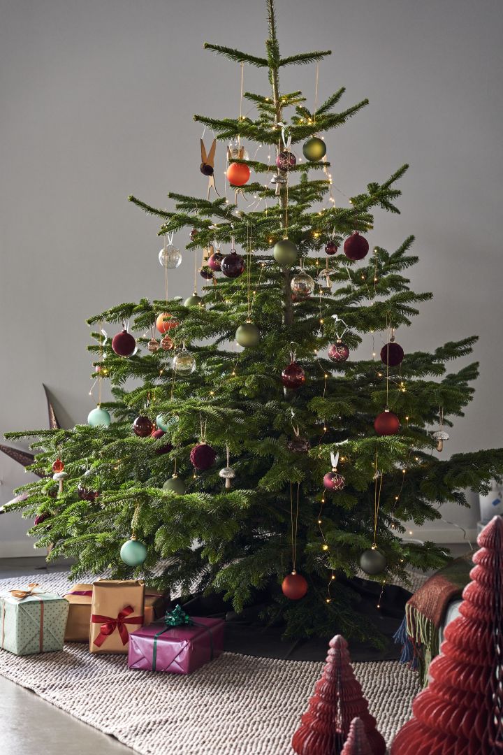 Decorate the Christmas tree with Christmas tree decorations for 2021 in 4 different styles according to Nest Trends - Nurture, Share, Boost and Cultivate. Here you see a magnificent tree on Scandi Living Flock wool rug in beige with decorations in deep rich colours and shades of red, orange and green.