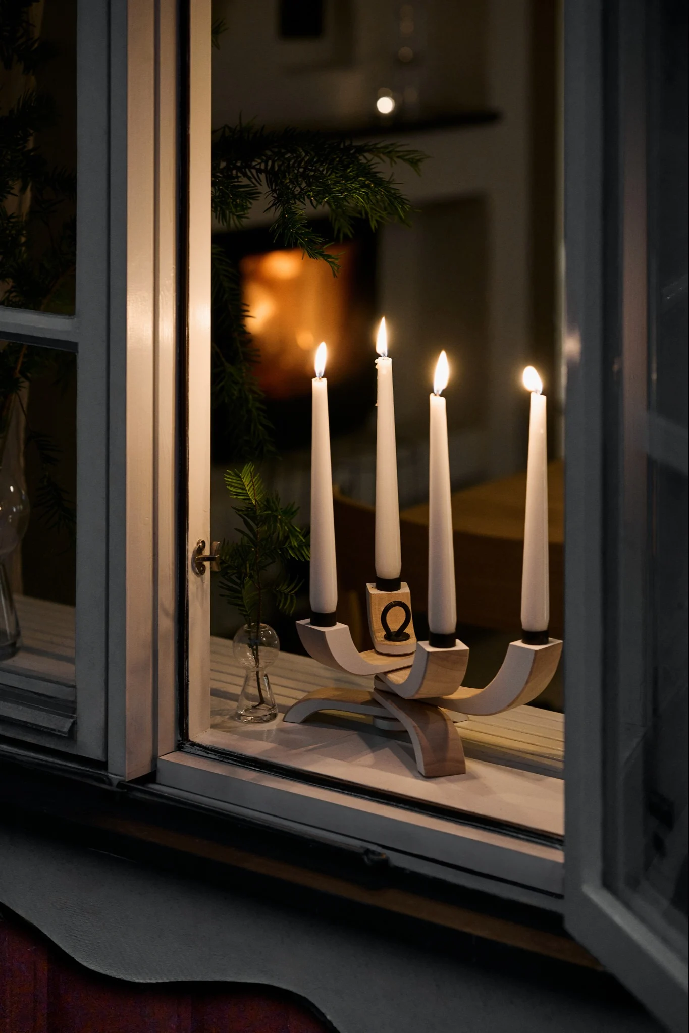 In the window stands an Advent candle holder with real candles spreading their warm glow into the darkness.