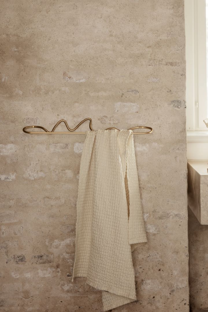 Wavy shapes are a clear trend among interior design 2022 - here a curved towel hanger from Ferm Living in brass.