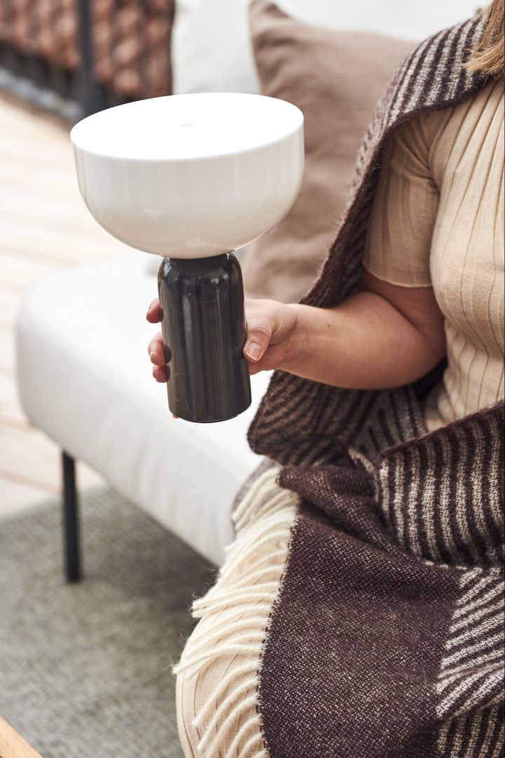 The cordless table lamp Kizu from New Works is held in a hand.