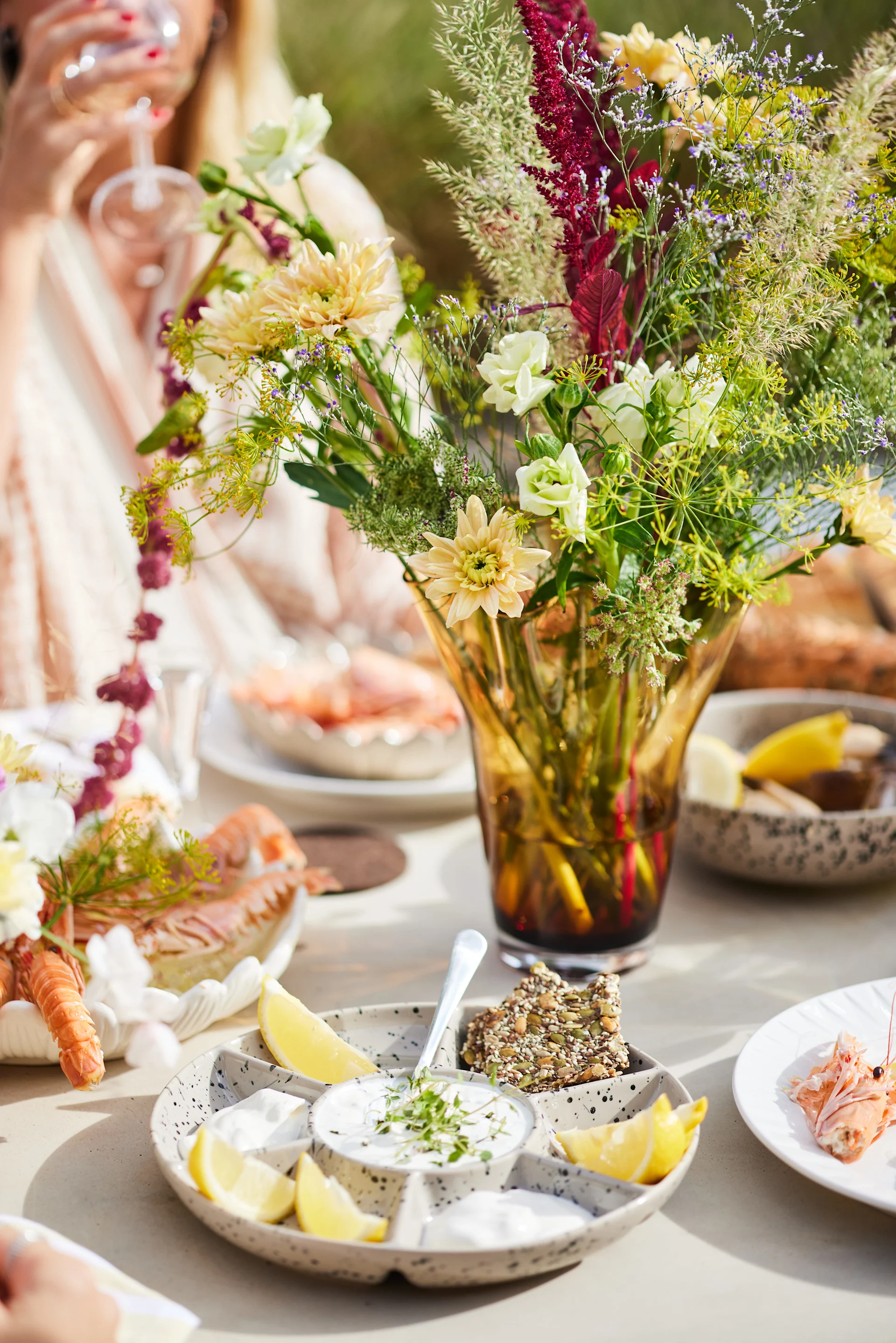 A table set for a Swedish crayfish party with a bouquet of flowers in the yellow Viva vase and the Ditte serving plate, both from Sagaform.