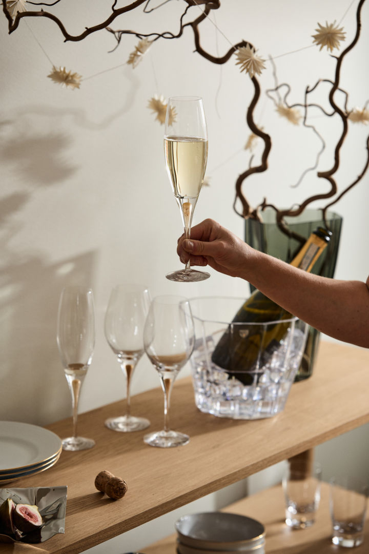 A hand holds up the Intermezzo champagne glass from Orrefors. 