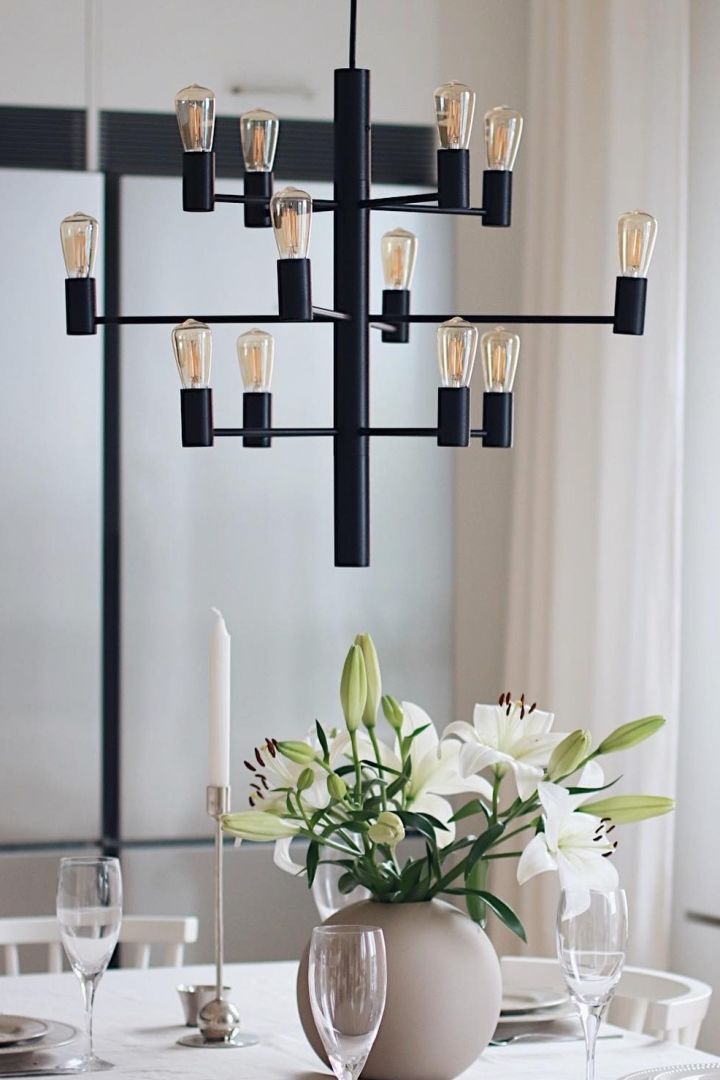 11 stylish ceiling lights to decorate your home with - here you see the Manola 12 Chandelier from Herstal hanging about a bunch of fresh flowers in beige room. 
