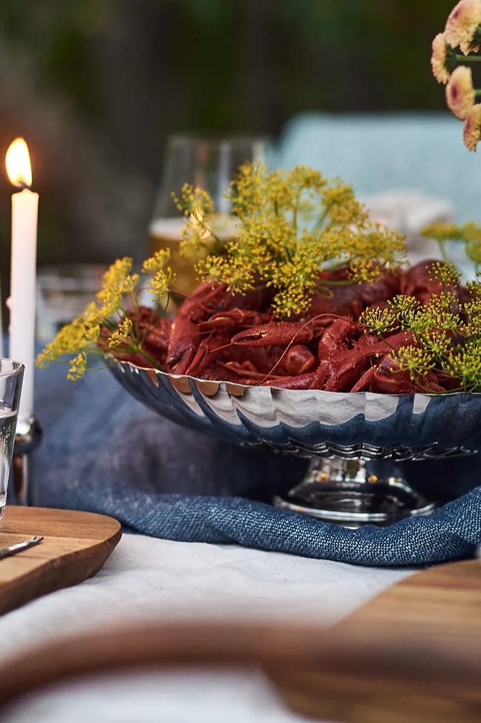 Here you see the Bernadotte serving bowl in chrome with crayfish in it on a set dinner table, ready for a Swedish crayfish party. 