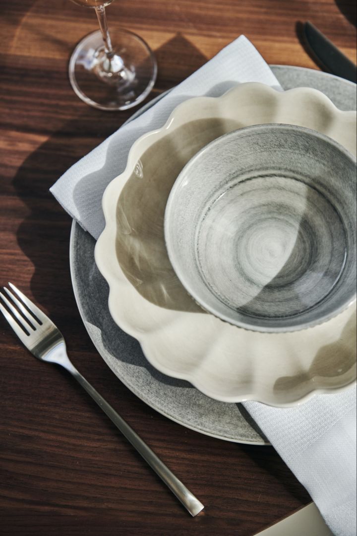 A place setting with beige oyster bowl in the colour sand and the grey bowl, plate and mug from the Basic, MSY, Strips and, Oyster series' from Mateus. 