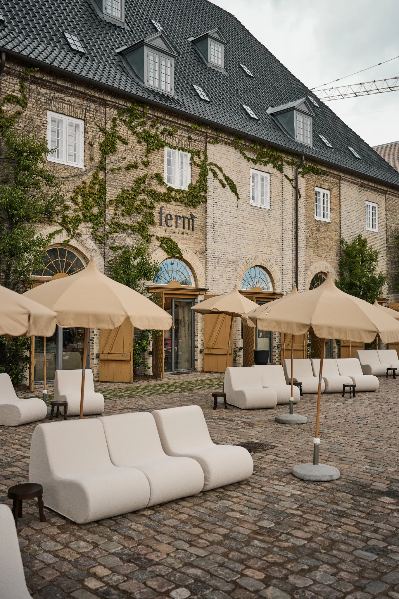 The area home to ferm LIVING should not be missed on a Copenhagen city guide for design lovers. Here you see the restored 18th Century building with module sofas and parasols outside.