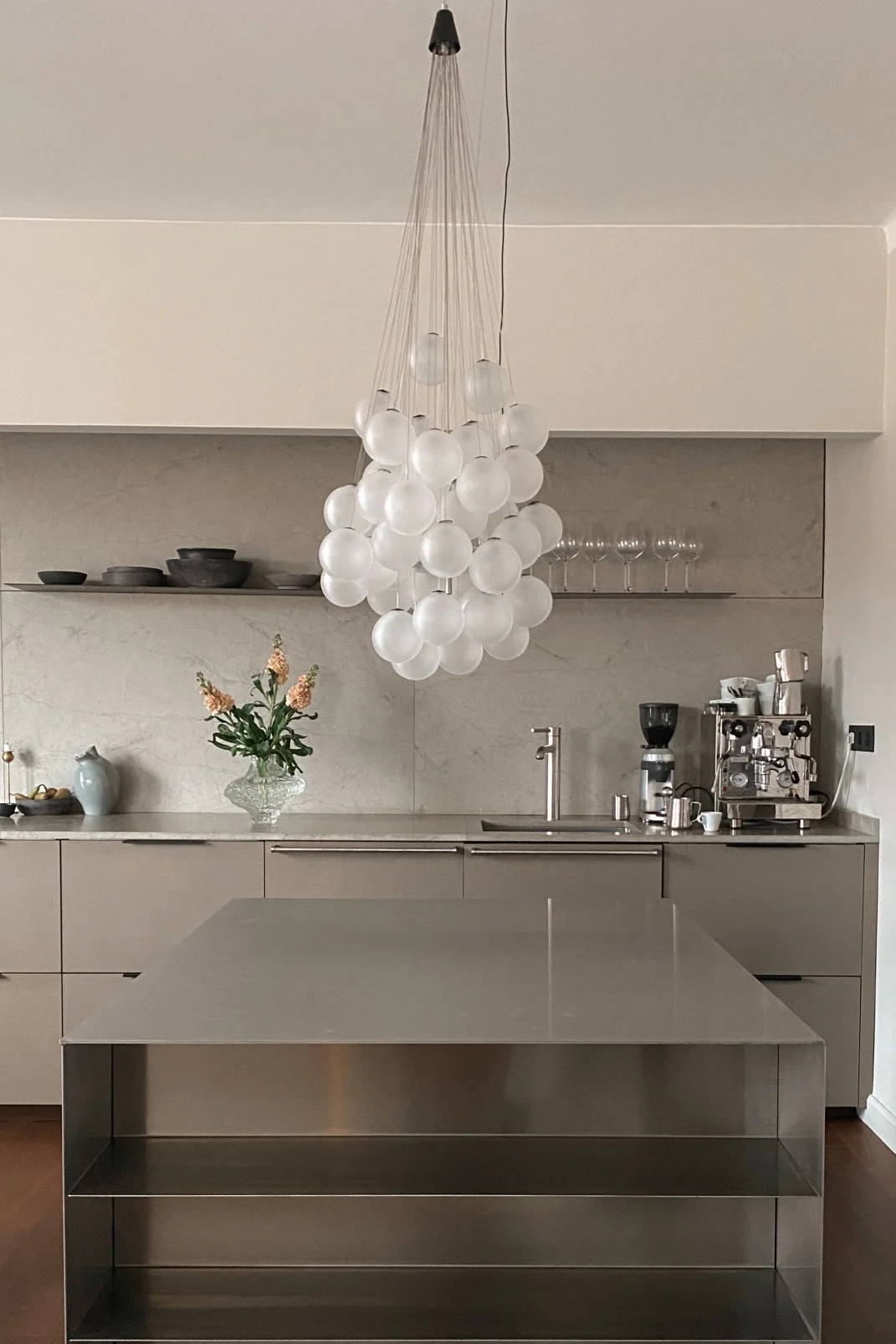 Refresh your home with modern lighting design. Here you see the Stochastic ceiling lamp from Luce Plan, a collection of glass balls hanging in a group above a stainless steel work bench.