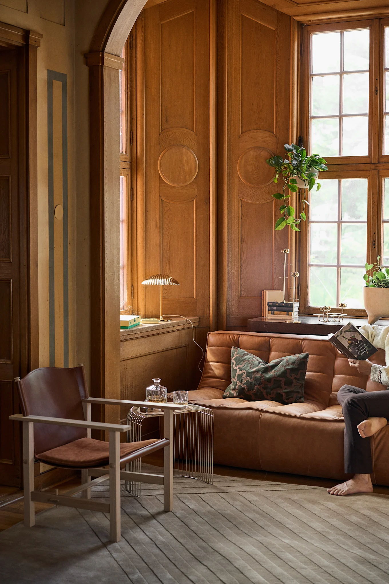 A room with wood paneling and a brown leather sofa and armchair, reflecting 1960s style and the interior design trends of 2026.