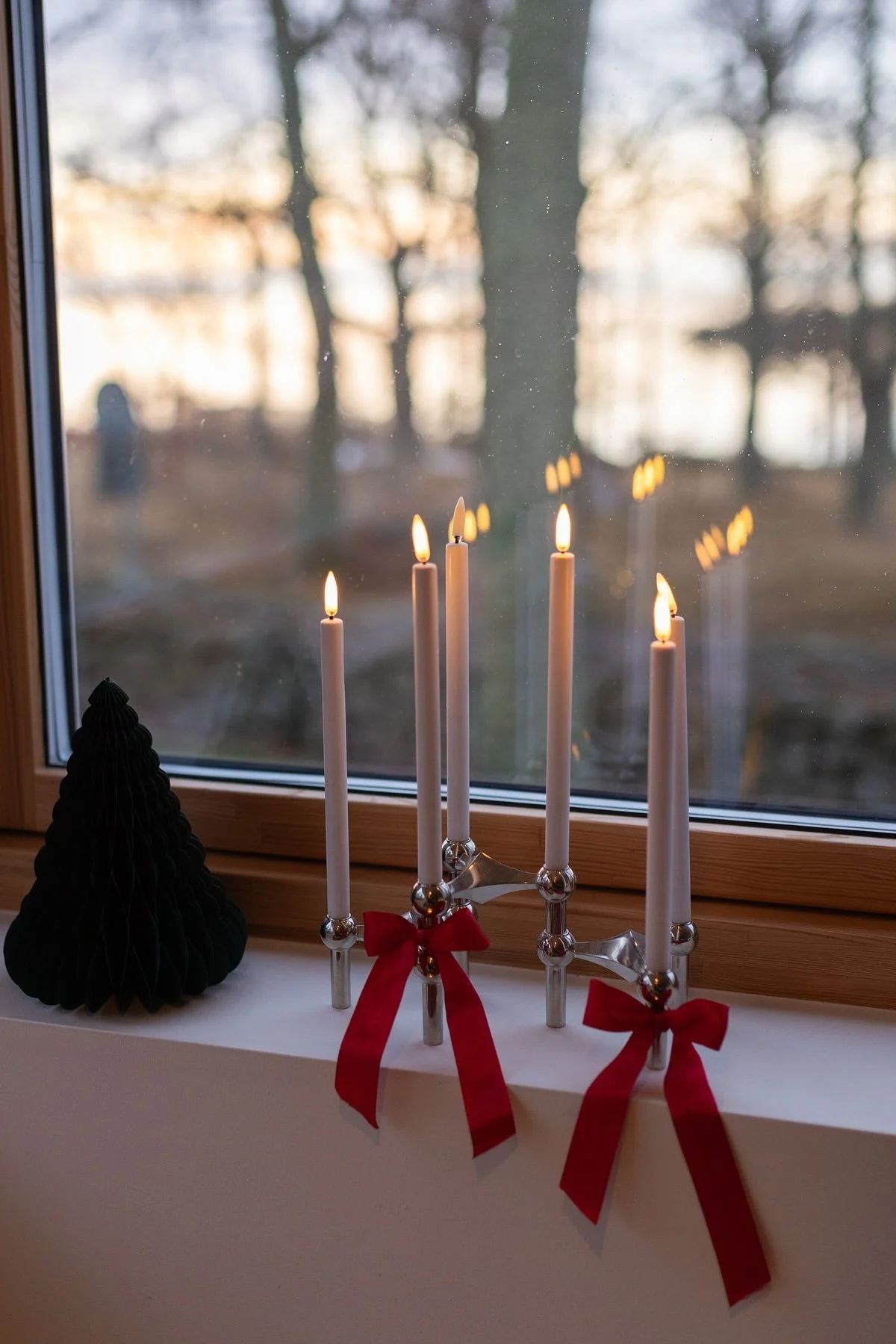 Bows are a trend in Christmas decorations for 2025. Tie some around the fabric nail candle holder and place it on the windowsill.