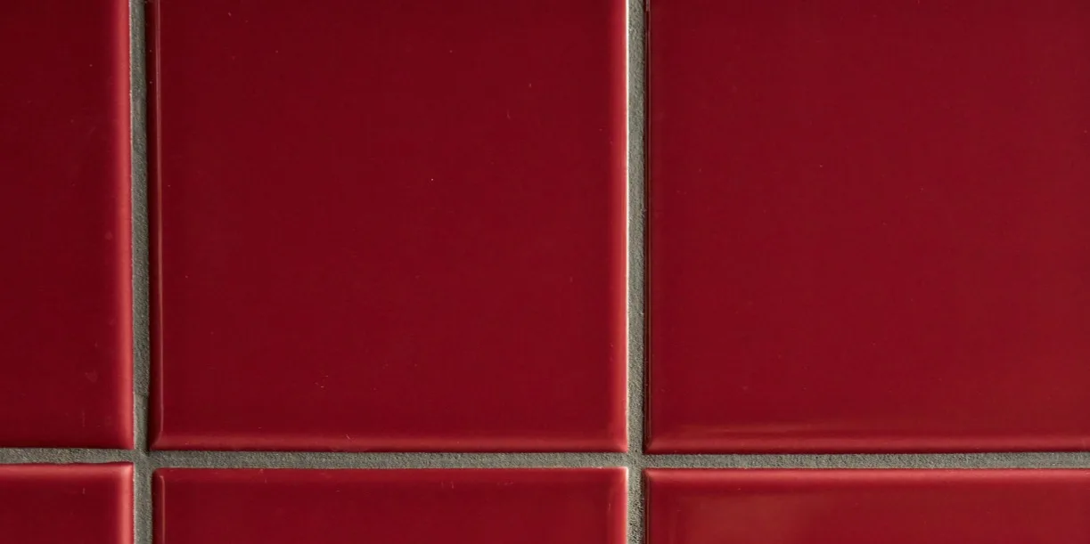 Glossy deep red square tiles with light grey grout in a grid pattern.