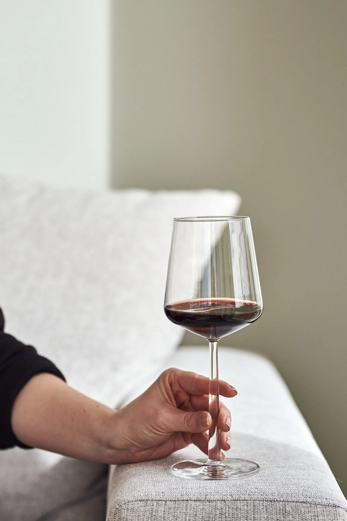 A hand holding a red wine glass that makes a perfect Christmas gift for the holidays.