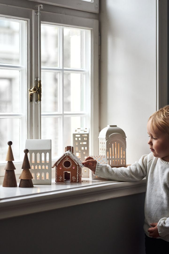 Decorate with traditional Scandinavian Christmas decorations like the Urbania candle holders from Kähler. Here you see a collection of them in the windowsill with a young boy. 