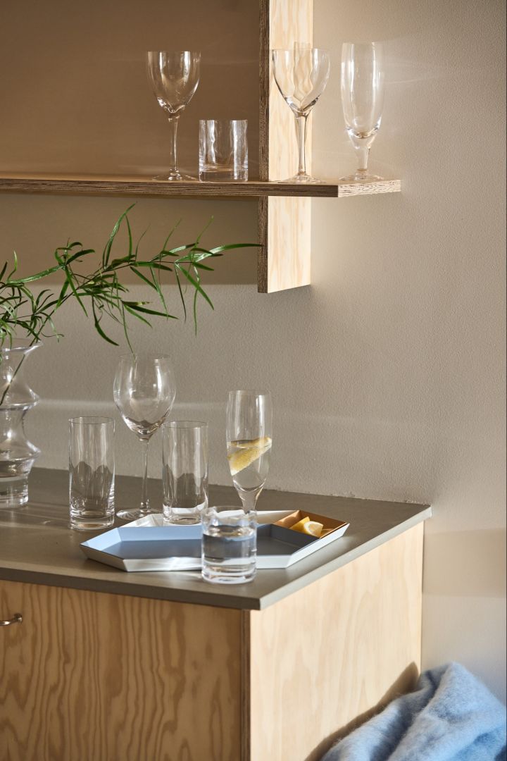 A collection of drinking glasses in different sizes and styles from the Chateau collection from Kosta Boda are collected on a kitchen side. 