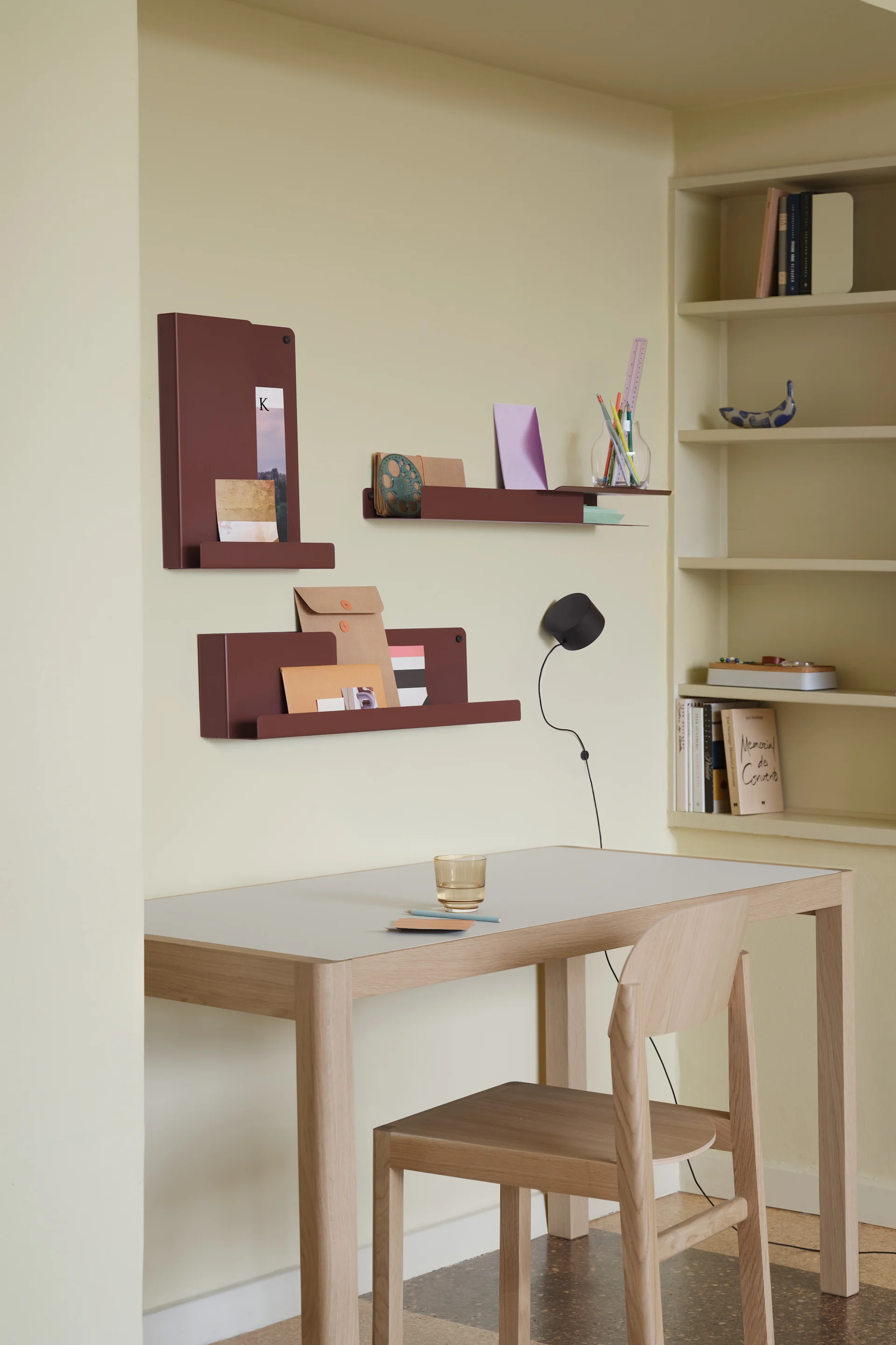 Home office with light wood desk and chair, reddish-brown wall shelves, and a bookshelf.