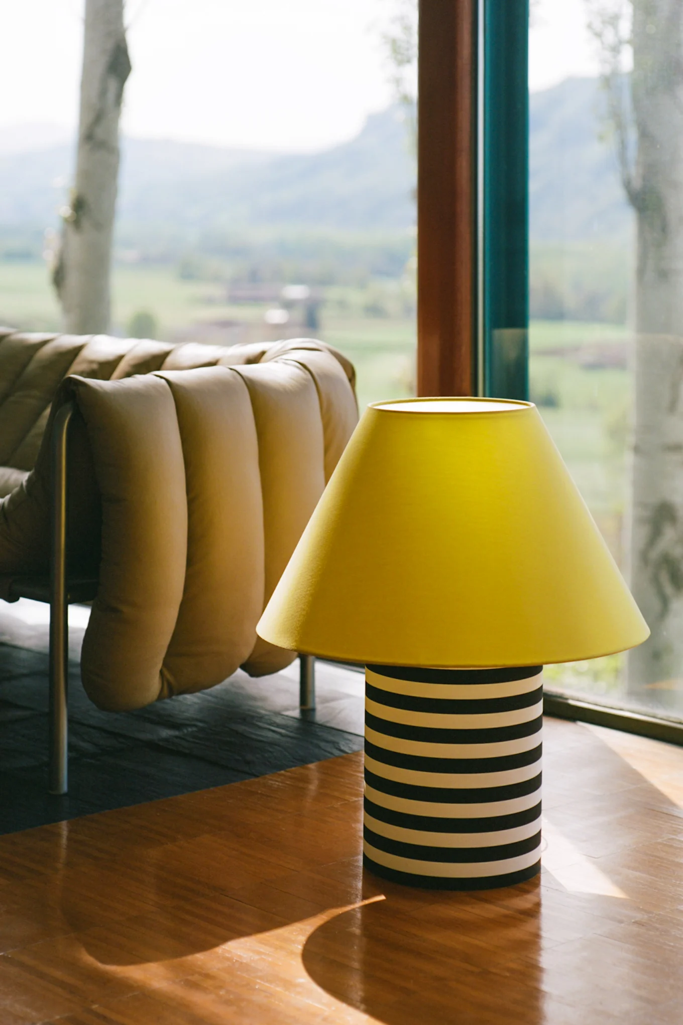 A large floor lamp with a striped base and a yellow shade that conveys a playful feel and reflects the interior design trends of 2026.
