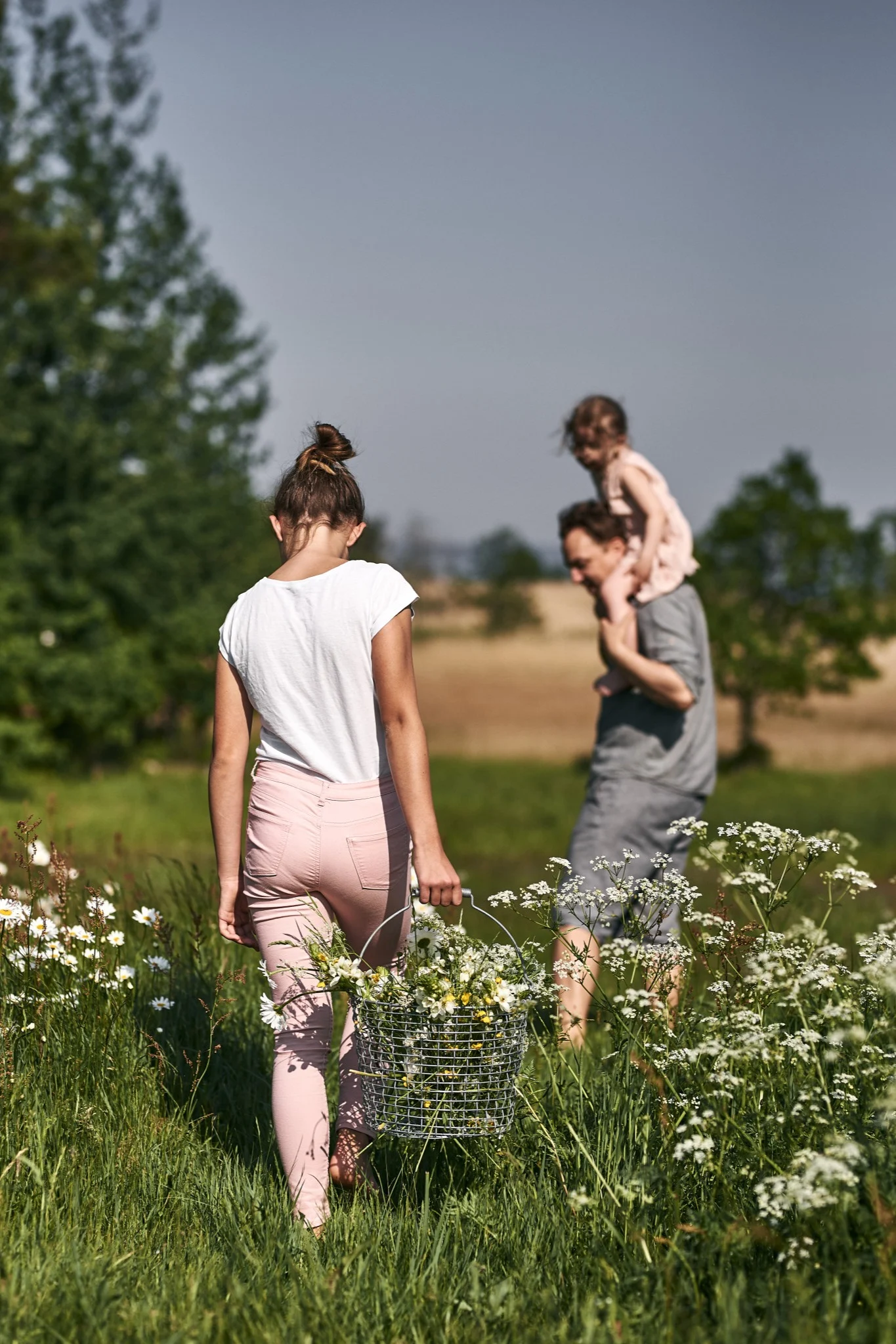 A girl picks flowers in the sunshine and places them in a Korbo basket. Swedish summer is all about spending time outside so be sure to include this on your summer bucket list ideas. 