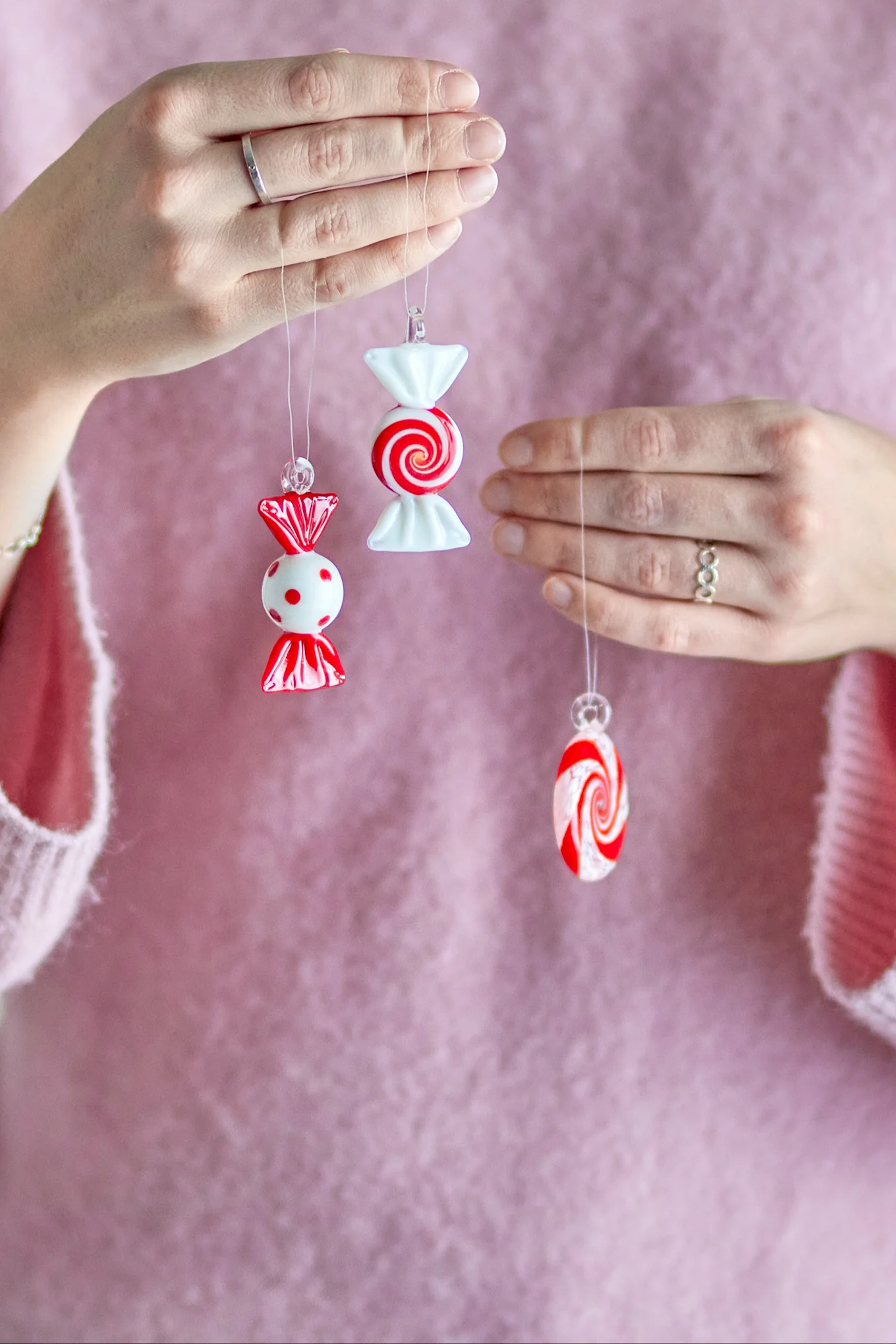 Christmas decorations 2025: A woman holds up three festive candy-shaped decorative pendants from Bloomingville for the camera.
