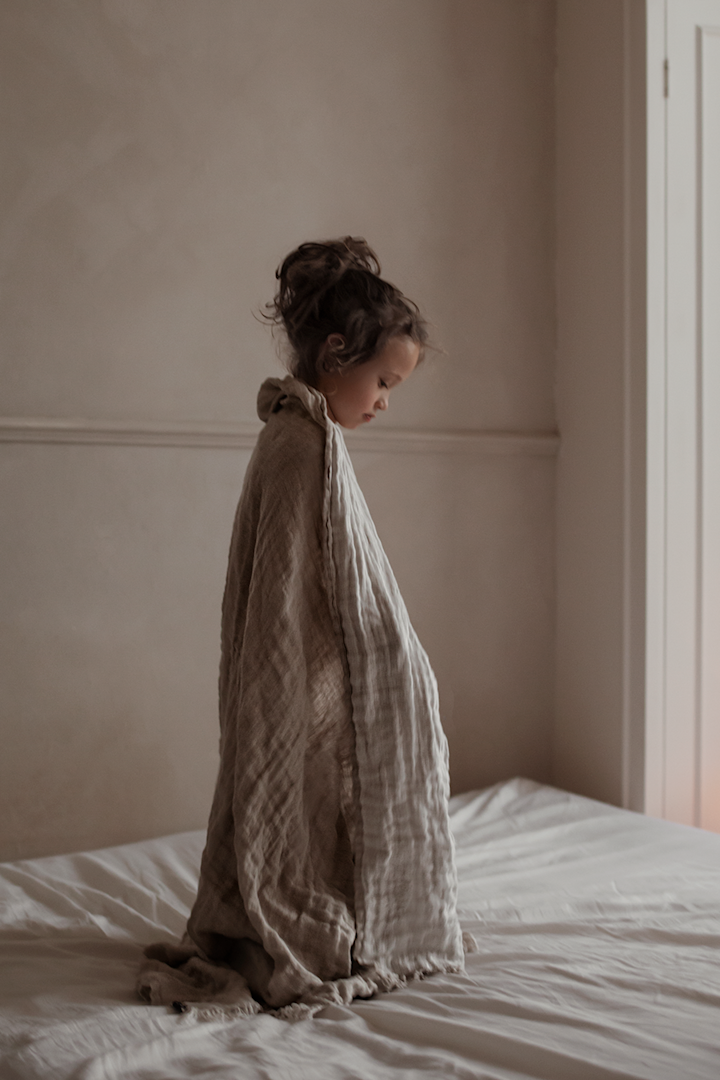 A boy stands in a window drapped in the Hannelin linen throw from Himla. 