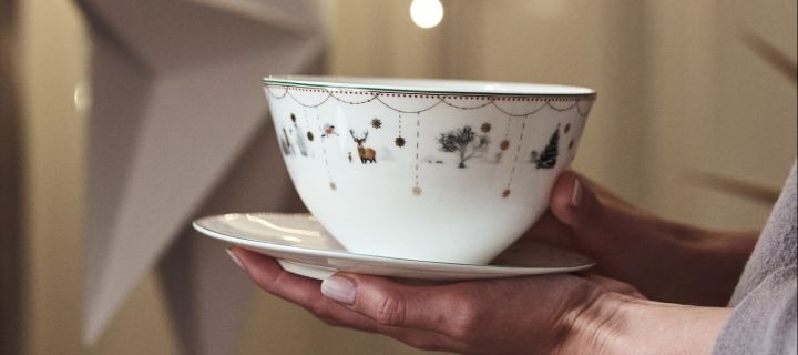 Here you see a close up of some hands holding the Wik & Walsøe Julemorgon Christmas cup and saucer. 