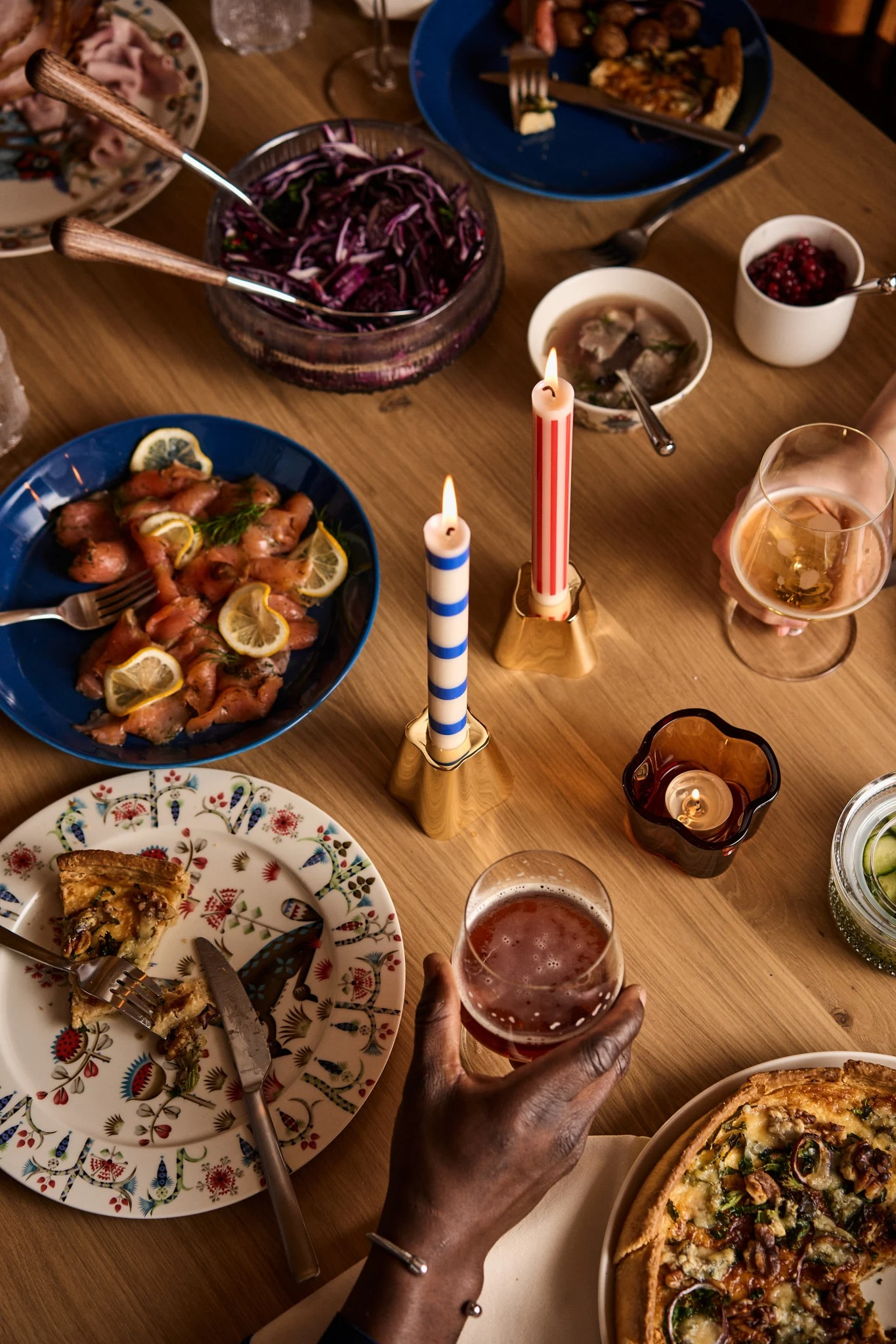 Friends cheers over a Nordic Christmas table with colourful plates and Christmas food. 