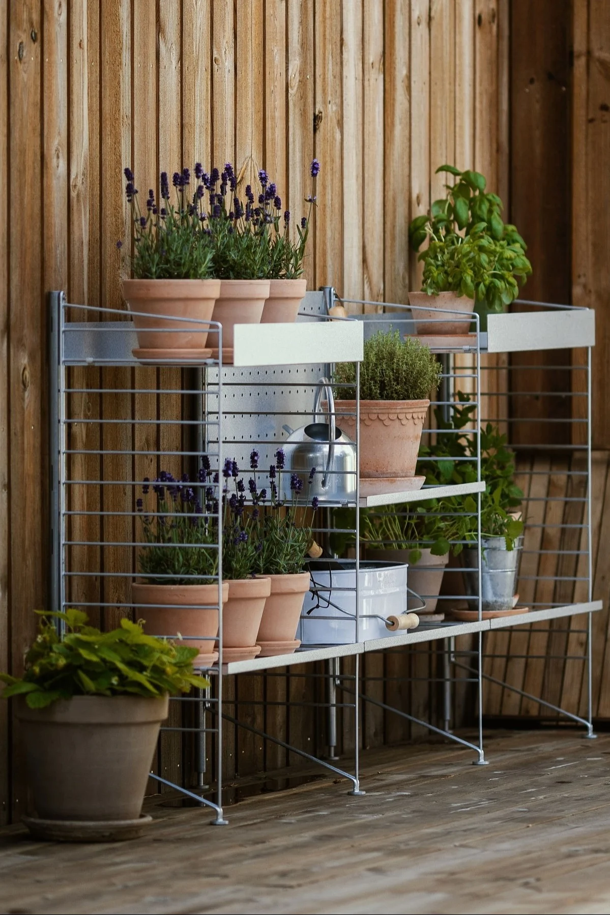 An outdoor shelf from String stands on @applaudden's terrace, filled with several plants in Bergs Potter flower pots from the Copenhagen collection.