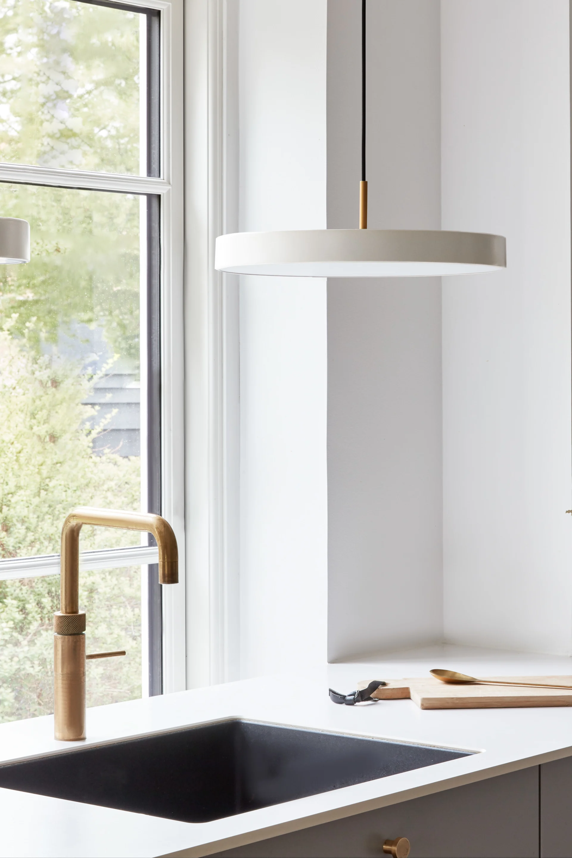 Use large pendant lights if you need a little more light in places like the sink. Here you can see the Asteria Micro pendant light in pearl white from Umage hanging above a sink.