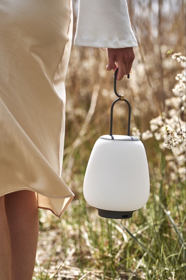 The cordless table lamp Lucca from &Tradition is carried on a beach.