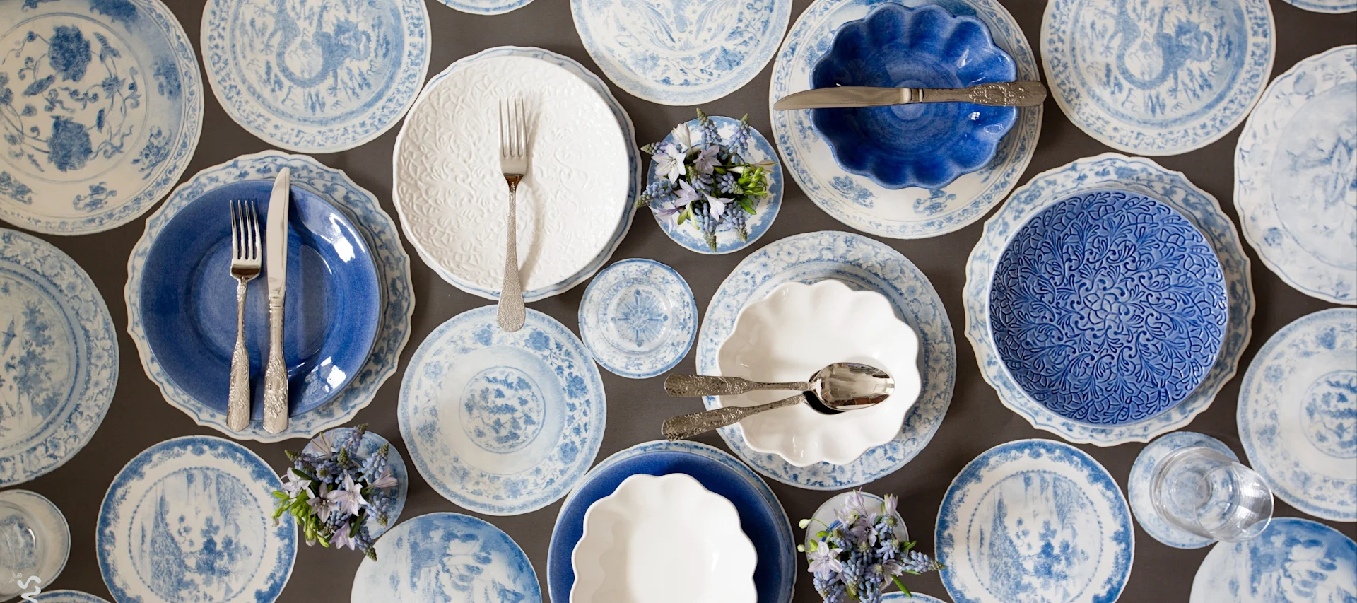 Plates and bowls from Mateus in the colours white and blue from different collections on one table.