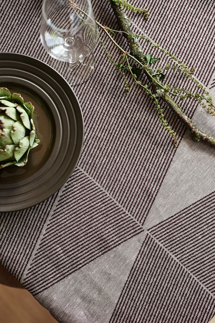 The Geometric tablecloth from NJRD in brown with a brown lines plate and a green artichoke. 