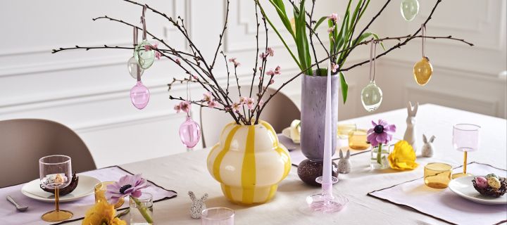 Create a festive Easter table setting in spring pastels with an Easter branch in colourful vases such as Curlie vase from By On and Dorit vase from Broste Copenhagen.
