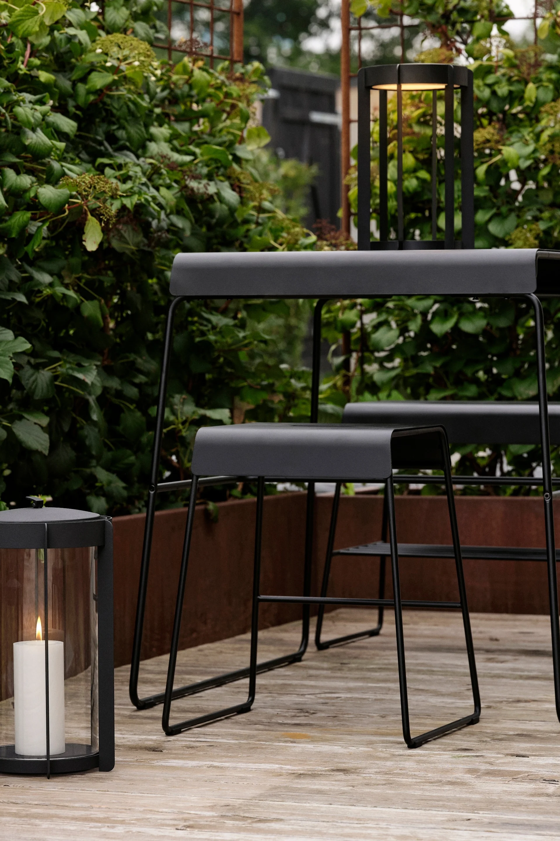 The table and stool from Zone Denmark's outdoor collection can be found outside on a patio.
