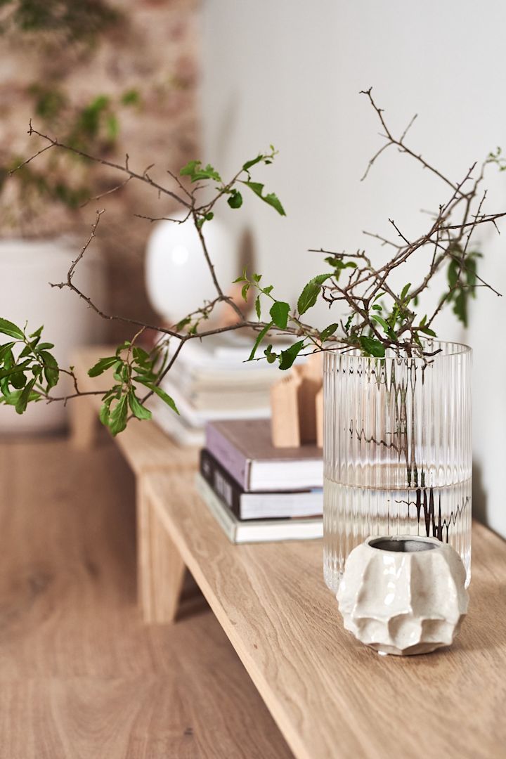 Interior details in the Japandi style with a glass vase and a simple green branch.