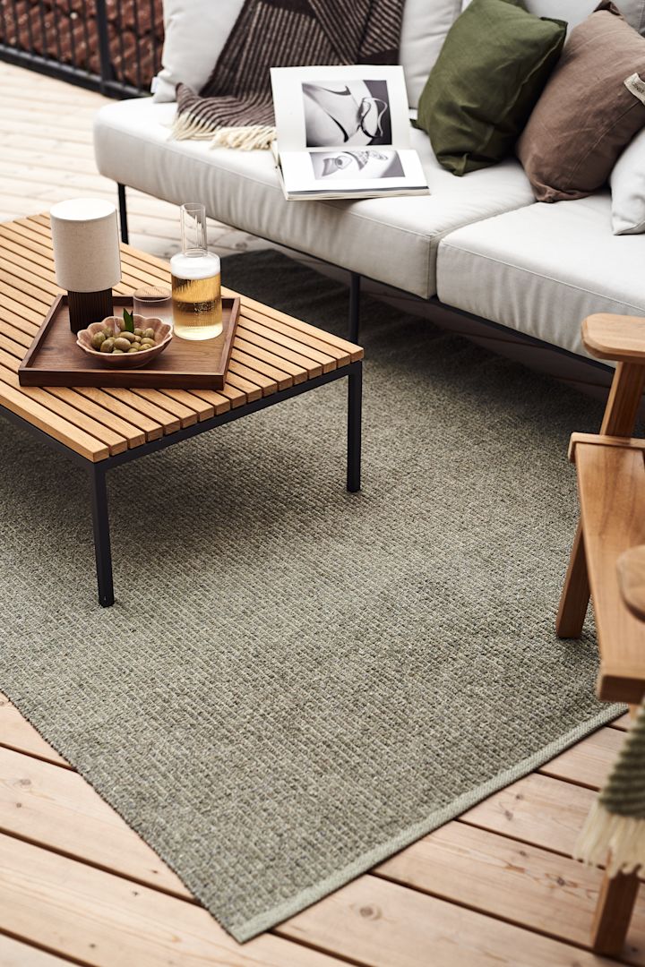 Here we see balcony inspiration in the form of a balcony rug. The large plastic rug Mellow in green from Scandi Living is placed under a lounge group with light-coloured cushions and a low teak table.