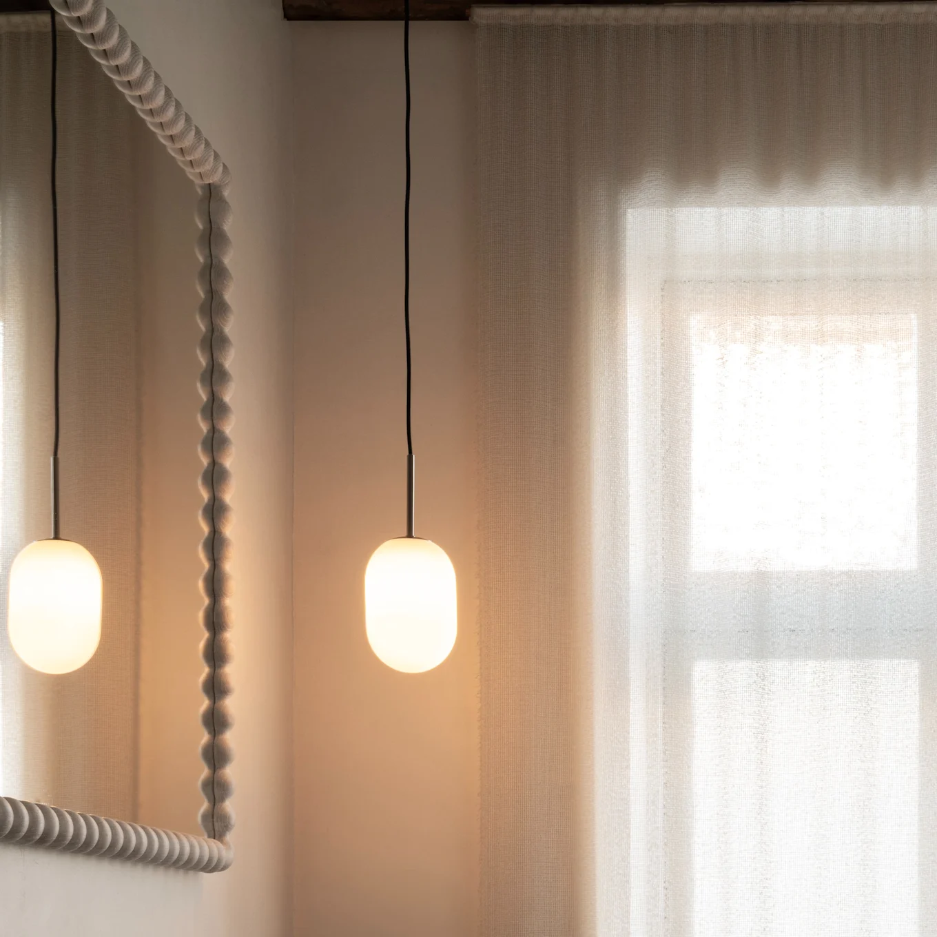 Modern bathroom: wood vanity, dark sink, bronze faucet, textured mirror, pendant lights, sheer curtains.