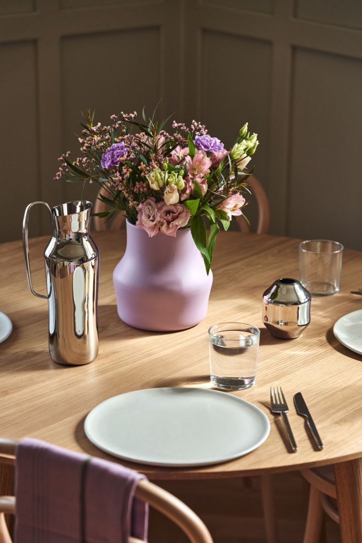 The lilac Dorotea vase on the table with the stainless-steel jug and mini vase from the same collection. 